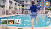 A child is joyfully jumping into a swimming pool at a hotel, with amenities like free WiFi, shuttle, and breakfast advertised in the foreground.