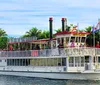 The image depicts a group of passengers enjoying a sightseeing tour on a paddlewheel boat named Carrie B