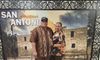 Two people are posing with smiles in front of a photographic backdrop that features the Alamo in San Antonio.