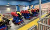 People are seated on a stationary amusement park ride with brightly colored seats and a sign indicating larger seats are available.