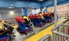 People are seated in a Superman-themed roller coaster ride, preparing for takeoff.