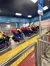 People are seated in a Superman-themed roller coaster ride, preparing for takeoff.