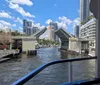 A drawbridge is raised over a waterway framed by modern skyscrapers under a blue sky with scattered clouds.