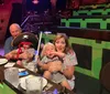 A family with two young children, one dressed as a pirate, is sitting at a table in an enclosed venue with green and brown seating.