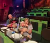 A family with two young children, one dressed as a pirate, is sitting at a table in an enclosed venue with green and brown seating.