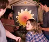 Four people are engaging in an escape room puzzle working together to solve a challenge involving a circular sun-shaped artifact with puzzle pieces