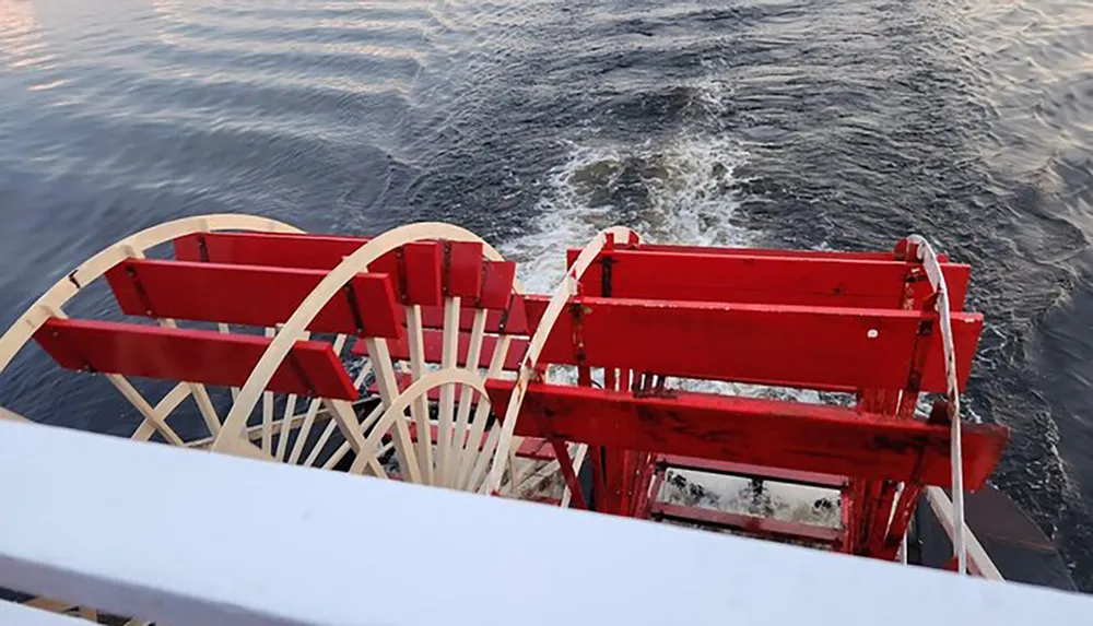 The image shows the red paddle wheels of a paddle steamer churning through the water