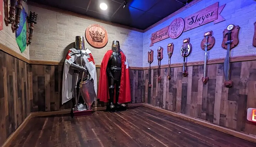 The image shows a themed room with two sets of armor on display alongside shields and axes mounted on the wall with the words Dragon Slayer featured prominently