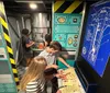 A group of people are engaging in what appears to be an escape room challenge surrounded by themed decorations that simulate a technical or possibly spacecraft environment