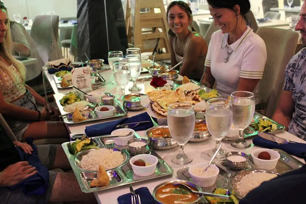A group of people is enjoying a meal together at a restaurant with various dishes and drinks spread out on the table