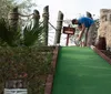 A family of four is enjoying a game of miniature golf with a pirate ship backdrop