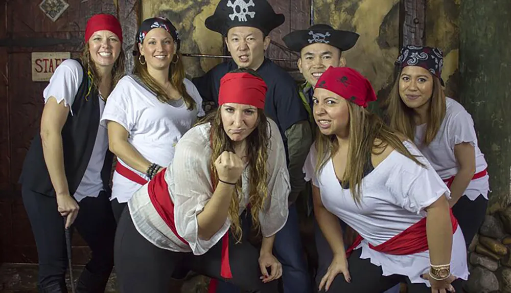 A group of people is playfully dressed as pirates posing in a themed setting with enthusiastic expressions