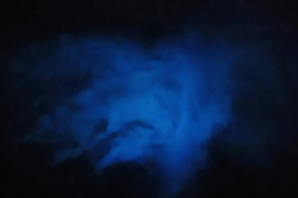 The image depicts a blurry blue and black abstraction that may resemble smoke light or a form of gas with a mysterious and eerie atmosphere