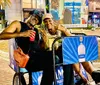 A smiling couple is enjoying a ride on a pedicab adorned with a tequila advertisement in an outdoor setting during the evening