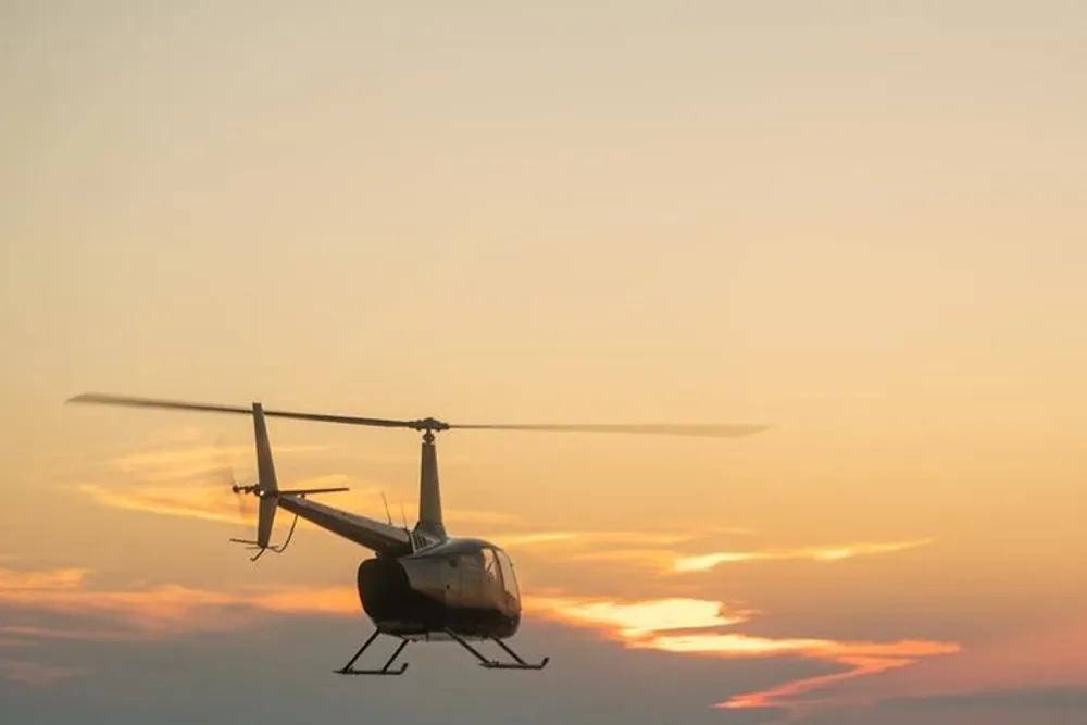 A helicopter is flying against the backdrop of a beautiful sunset sky