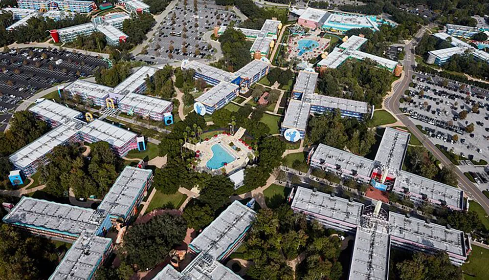 The image shows an aerial view of a large resort complex with colorful buildings swimming pools and parking lots scattered among greenery