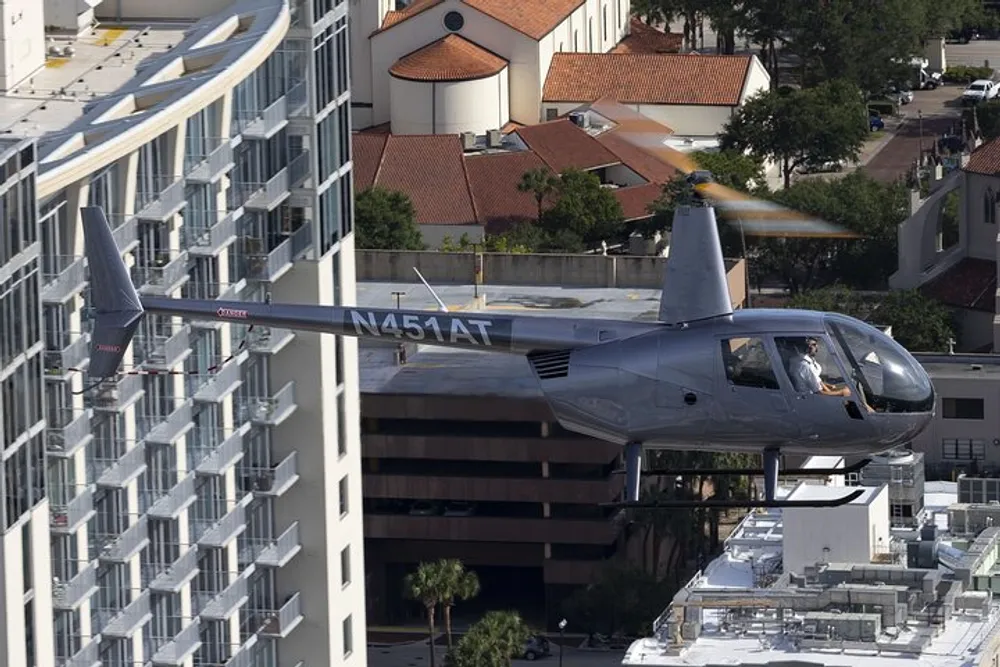 A small aircraft is flying closely between high-rise buildings in an urban area