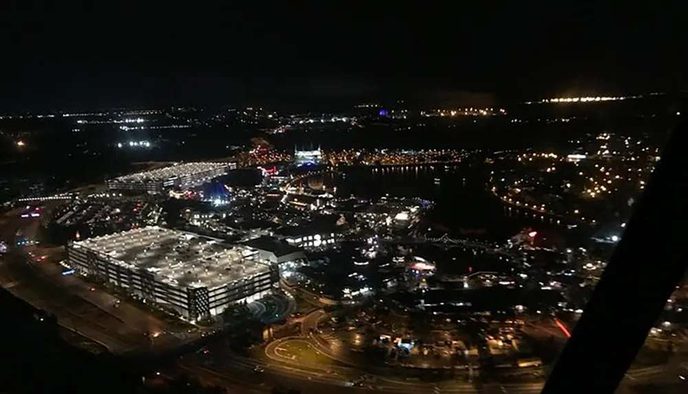 The image depicts a nighttime aerial view of an illuminated urban area with roads buildings and a waterfront