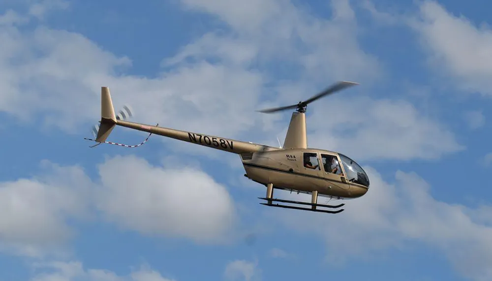 A helicopter is flying in a clear sky with a few clouds