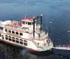 A traditional paddlewheel riverboat is cruising on calm waters under a clear sky