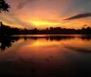 Two people are kayaking on tranquil waters under a pastel sunset sky