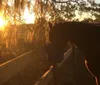 Two riders on horses are enjoying a vibrant sunset over a field peppered with yellow flowers