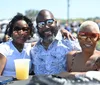 A smiling man wearing sunglasses is holding a child who is also wearing sunglasses as they seem to enjoy an outing together possibly getting some ice cream