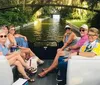 A group of friends is enjoying a leisurely boat ride along a canal lined with lush greenery