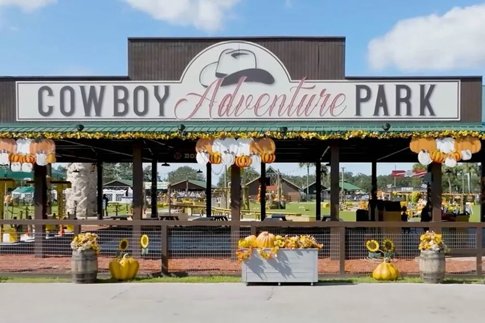 The image shows the entrance of Cowboy Adventure Park adorned with festive pumpkin decorations reflecting a seasonal or holiday theme