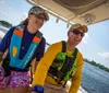 Three people wearing life jackets are enjoying a sunny day on a small motorboat with a Bimini top on a calm water body