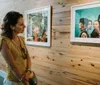 A woman is observing framed photographs displayed in an art gallery with wooden walls