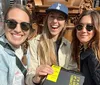 Three happy individuals are posing for a selfie on a sunny day with one of them holding a book that has a yellow post-it note on its cover