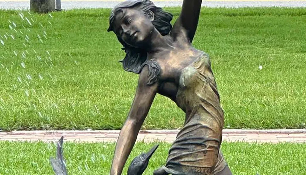 The image shows a bronze sculpture of a girl doing a cartwheel with water droplets captured in motion to create the illusion of rain