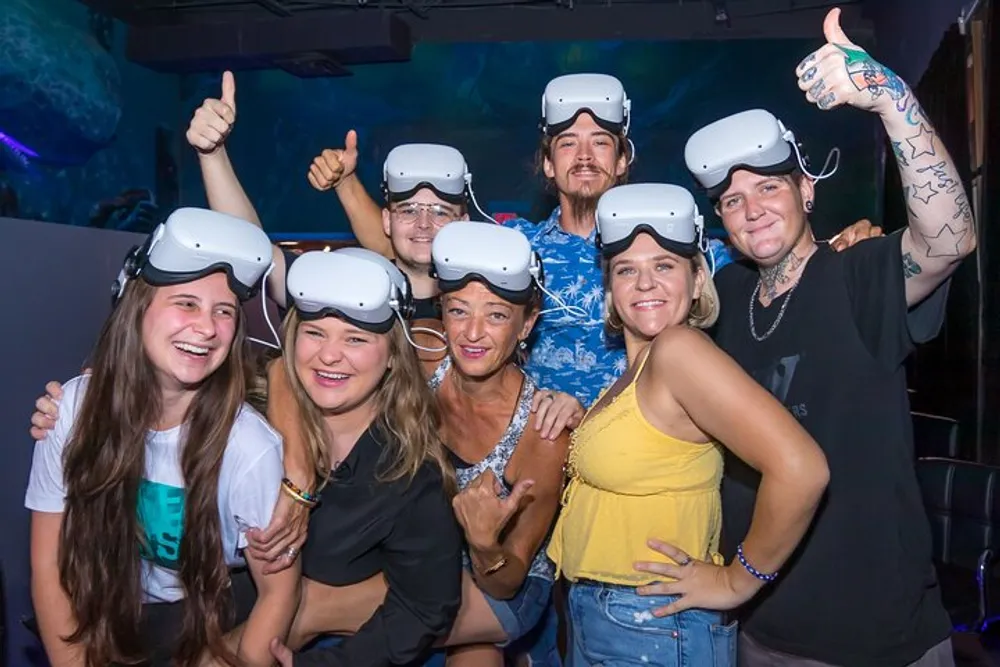 A group of cheerful people are wearing VR headsets and giving thumbs-up likely enjoying a virtual reality experience together