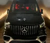 A black Mercedes-Benz van is parked indoors illuminated by soft lighting that highlights its luxury front grille design