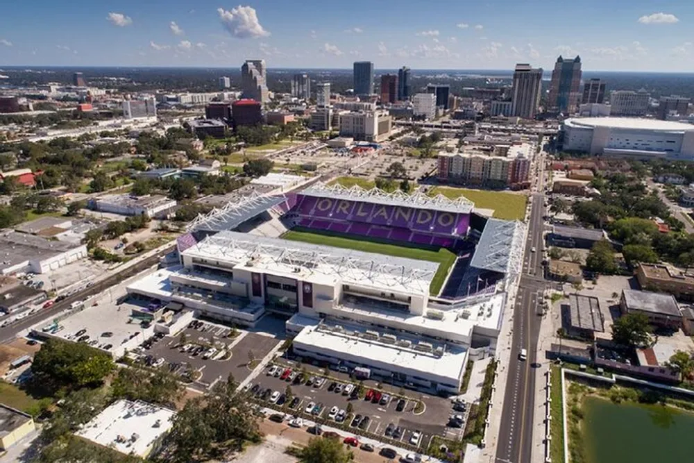 Aerial view of a stadium with ORLANDO prominently displayed surrounded by urban infrastructure and buildings in the backdrop