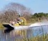 A group of people is enjoying a ride on an airboat through a waterway surrounded by vegetation