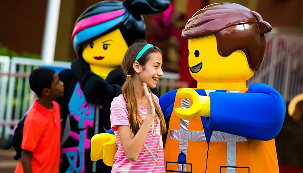 A girl interacts with life-sized LEGO characters at an amusement park