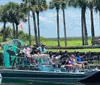 A group of people is enjoying a ride on an airboat among palm trees likely on a guided tour in a wetland area