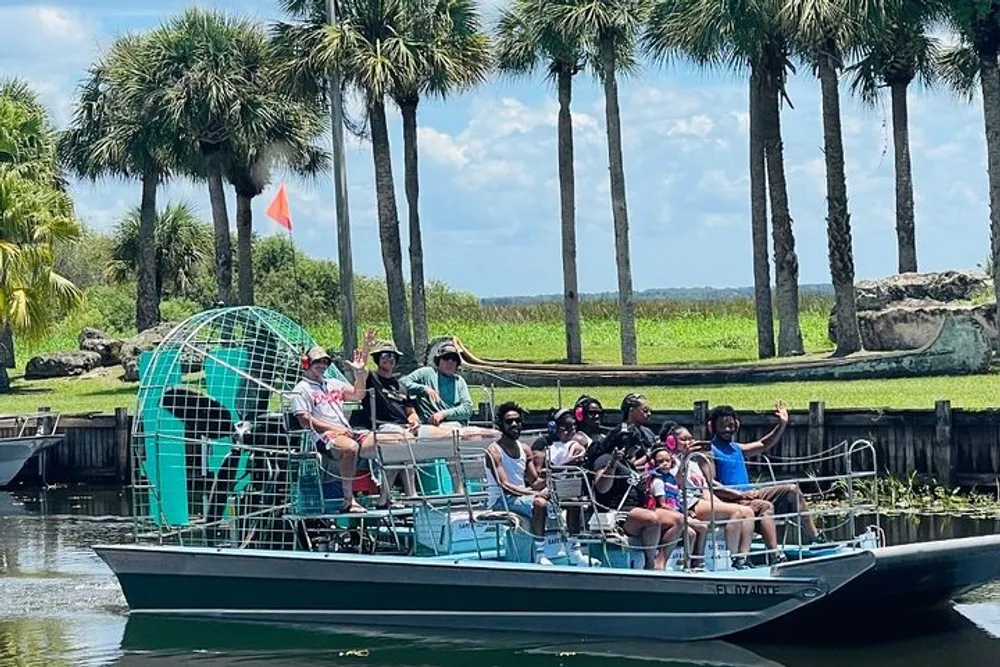 A group of people is enjoying a ride on an airboat among palm trees likely on a guided tour in a wetland area