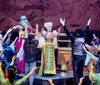 Four performers in blue costumes ride unicycles and hold hands on stage under bright lights part of the Drawn to Life Cirque du Soleil and Disney show