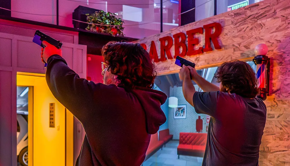 Two people holding guns are standing in front of a barber shop storefront in a colorful possibly simulated environment
