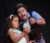 A magician wearing a hat is showing a card trick to a young girl on stage both looking at the cards shes holding