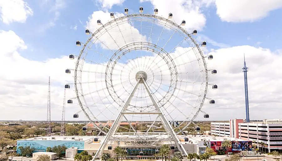 A large Ferris wheel dominates the skyline above other buildings under a partly cloudy sky.