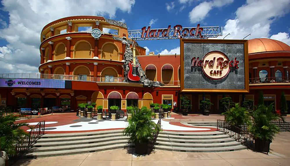 This image shows the iconic facade of a Hard Rock Cafe with its signature guitar and logo under a clear blue sky