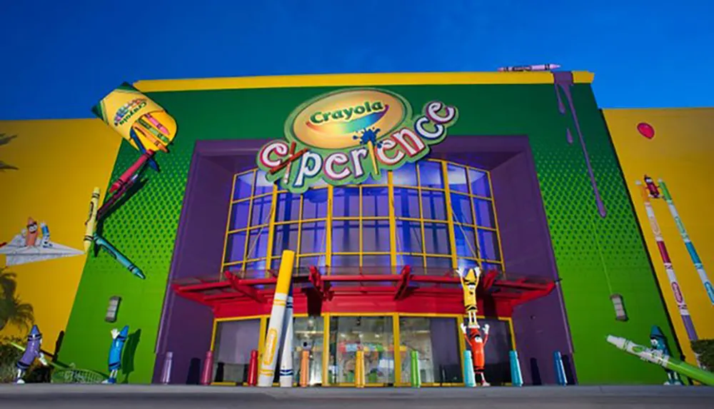 The image shows the vibrant and colorful facade of the Crayola Experience attraction with oversized crayon decorations