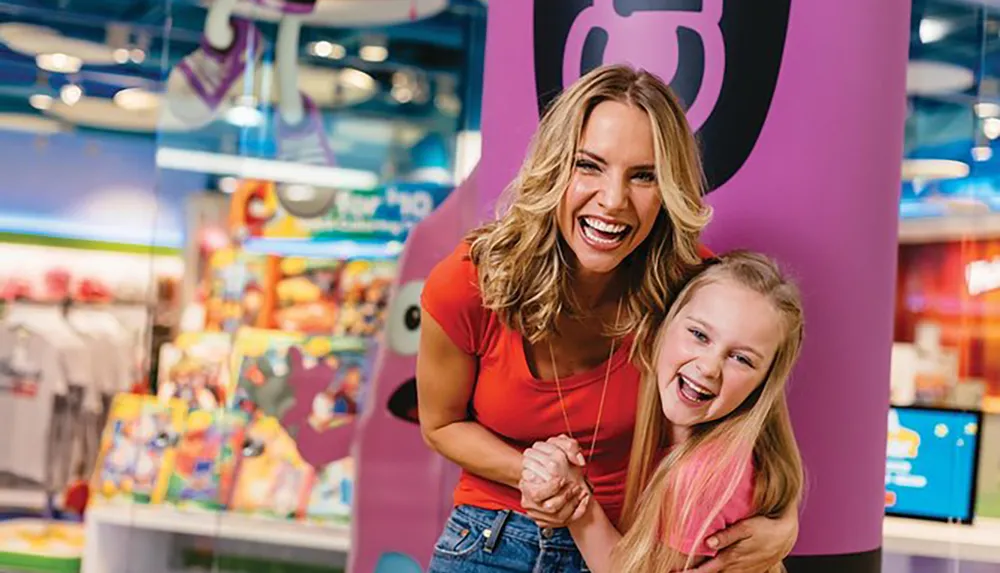A joyful adult and child are smiling and posing for a photo in a vibrant toy store setting