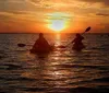 Two people are kayaking on the water during a beautiful sunset
