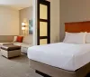 The image shows a neatly arranged modern hotel room with a bed sofa and decorative lighting