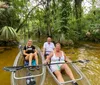 Three individuals are enjoying a canoe trip on a tranquil tree-lined river
